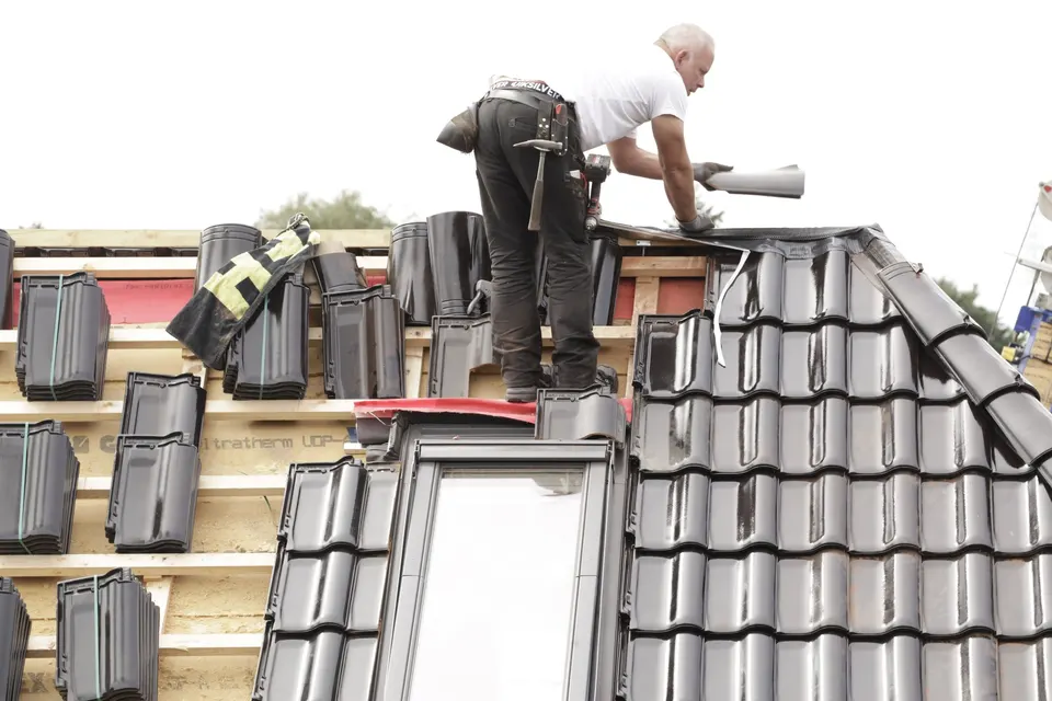 A roofer laying tiles on a house roof